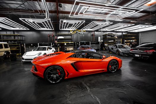 High-end sports cars displayed in a sleek, modern showroom with stylish lighting.