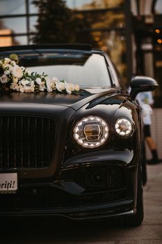 Elegant black luxury car adorned with flowers, parked outdoors in Arad, Romania.