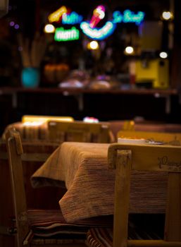Warm, inviting restaurant interior featuring empty tables, soft lights, and colorful neon signs.